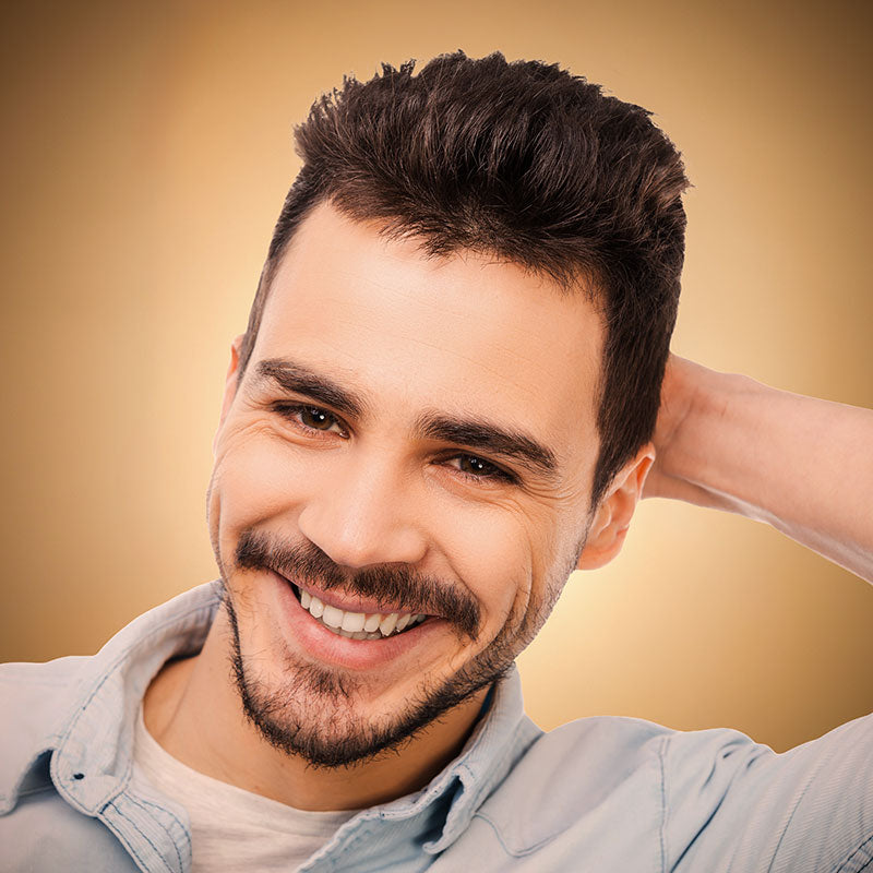 Man with a beard and short hair smiling against a beige background